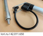 Sports tools: aluminum hand pump next to bicycle pump with support bracket. Light alloy compact pumps with attached adapters: for inflation needles, and another with a black hose for bike' nipples. Стоковое фото, фотограф Анатолий Власов / Фотобанк Лори