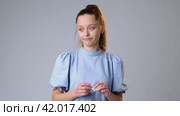 Doubtful young woman refusing gesture hesitating on gray background in studio. Стоковое видео, видеограф Сергей Толмачёв / Фотобанк Лори