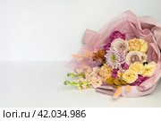 Beautiful festive bouquet of fresh flowers, delicate roses, carnations and pink chrysanthemums in festive packaging on white background. Empty space for text. Romantic gift for Valentine's Day, March 8, Mother's Day, Birthday or family holiday. Стоковое фото, фотограф Виктория Катьянова / Фотобанк Лори