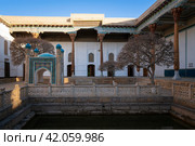 View of the courtyard of the Bahauddin Naqshbandi Memorial Complex with a pond and a chartak in the foreground on a sunny day, Bukhara, Uzbekistan. Стоковое фото, фотограф Ula Ulachka / Фотобанк Лори