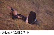 A young girl is dancing lying in the dry grass. Стоковое видео, видеограф Strunov David / Фотобанк Лори