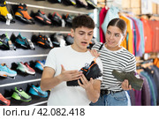 Guy with girlfriend, view specialized shoes in store, near showcase with summer trecking cross-shoes. Стоковое фото, фотограф Яков Филимонов / Фотобанк Лори