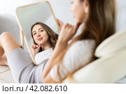 Satisfied young woman patient holding mirror lying on clinical chair. Стоковое фото, фотограф Яков Филимонов / Фотобанк Лори