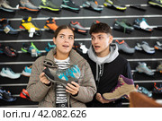 Couple examine view several item of winter comfortable trecking shoes. Стоковое фото, фотограф Яков Филимонов / Фотобанк Лори