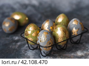 Stylish beautiful Easter eggs with golden potali coating on a gray background. The concept of happy Easter 2024. Стоковое фото, фотограф Photojuli / Фотобанк Лори