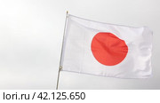 Big flag of Japan fastened on stick against background of blue cloudy sky under daylight. Стоковое видео, видеограф Яков Филимонов / Фотобанк Лори