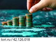 Human hand putting coin to stack of coins on green arrow background. Investment, saving money and finance growth business concept for poster or banner design. Стоковое AI-изображение, AI-художник Ирина Михайличенко / Фотобанк Лори