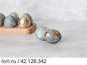 Stylish grey Easter eggs made of marble and concrete with a golden potala on a grey background. Coloring eggs with natural dye karkade tea. . The concept of a happy Easter. Стоковое фото, фотограф Photojuli / Фотобанк Лори