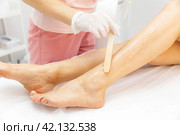 Cosmetologist applies gel to woman's legs for laser hair removal. Beautician doing laser rejuvenation in a beauty salon. Removing unwanted body hair. High quality photo. Стоковое фото, фотограф Ирина Михайличенко / Фотобанк Лори