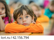 Boy with orange shirt at school desk. Стоковое AI-изображение, AI-художник Данил Руденко / Фотобанк Лори