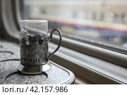 Glass in retro cup holders with the coat of emblem of Russia in the train by the window. Travel concept. (2021 год). Стоковое фото, фотограф Ирина Вершинская / Фотобанк Лори