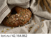 Хлеб каравай зерновой ржаной постный круглый на льняном кухонном полотенце. Стоковое фото, фотограф Оксана Шведкова / Фотобанк Лори