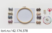 Video of accessories for hand embroidery - wooden hoop, cotton canvas, embroidery needles, pins, scissors and skeins of  natural thread on white background. Flat lay, close-up, top view. Стоковое видео, видеограф Виктория Катьянова / Фотобанк Лори