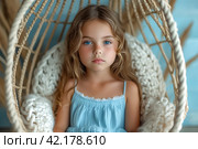 Cute happy little girl in blue dress sitting on white macrame cotton rope cocoon hanging. Child baby infant sits in a wicker hanging chair at home and relaxes. Стоковое AI-изображение, AI-художник Ирина Михайличенко / Фотобанк Лори