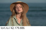 Woman in straw hat and green polka dot dress turning head, looking around on background of sea waves. Стоковое видео, видеограф А. А. Пирагис / Фотобанк Лори