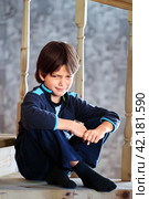7 year old European boy frowned while sitting on stairs at home. Стоковое фото, фотограф Владимир Григорьев / Фотобанк Лори