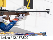 Sportswoman biathlete rifle shooting in prone position. Selective focus, extreme closeup shot. Biathlete in shooting range (2019 год). Редакционное фото, фотограф А. А. Пирагис / Фотобанк Лори