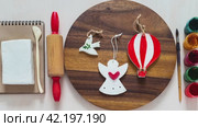 Making handmade gifts from air curing white clay. Piece of clay or modeling paste, rolling pin, paints, brush and crafts of bird, angel and ball on wooden tray. DIY concept, crafts and hobby. Video, close-up. Стоковое видео, видеограф Виктория Катьянова / Фотобанк Лори