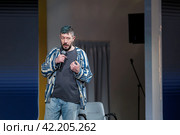 Confident male speaker with microphone at a casual event, engaging audience (2024 год). Редакционное фото, фотограф Антон Гвоздиков / Фотобанк Лори