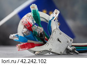 Закрытые наручники на сетевых проводах и флаг  Евросоюза на абстрактном фоне, концепция на тему наказания за преступления в сети. Стоковое фото, фотограф Сергей Чайко / Фотобанк Лори
