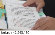 A priest holds a Bible in his hands (2023 год). Редакционное видео, видеограф Потийко Сергей / Фотобанк Лори