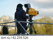 TV operator working at the city street during Victory Day celebration. Construction site as background. Business, industry and news concepts. Back, rear view. Стоковое фото, фотограф YuryKara / Фотобанк Лори