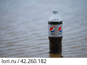 Istra, Russia - April 13, 2022: Photography of a popular soft drink Pepsi Cola. Bottle standing in the lake. Minimalism. Minimalistic concept. Plastic bottle. Volume is 1 liter. Редакционное фото, фотограф YuryKara / Фотобанк Лори