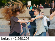 Moscow, Russia - May 21, 2022: Cheerful Dancing couple of young man and woman in public park. Lifestyle theme. Having fun people. People celevrate Victory Day, the win in the Great Patriotic War. Редакционное фото, фотограф YuryKara / Фотобанк Лори