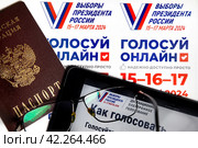 Паспорт гражданина РФ, электронный гаджет и рекламные листовки с информацией о выборах Президента РФ лежат на столе (2024 год). Редакционное фото, фотограф Николай Винокуров / Фотобанк Лори