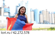 Sad young woman holding big flag of Mongolia against background of factory. Стоковое видео, видеограф Яков Филимонов / Фотобанк Лори