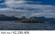 Small rocky islets in the Beagle Channel. Ripples on the blue water. The coastal mountain range of the Andes against the background of sky and clouds. Tierra del Fuego Archipelago. Argentina (2023 год). Стоковое фото, фотограф Вера Ивановна Кубарева / Фотобанк Лори