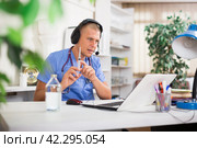 Doctor in headphones consults patient using laptop and the Internet. Virtual visit to hospital concept. Стоковое фото, фотограф Яков Филимонов / Фотобанк Лори