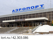 Аэропорт Братск, Иркутская область, Россия. Вид на здание аэровокзального комплекса. На крыше здания большая вывеска «АЭРОПОРТ». Над входом в аэровокзал текст «100 лет Гражданской Авиации России». Авиационная транспортная инфраструктура и авиасообщение в Восточной Сибири. (2024 год). Редакционное фото, фотограф Андрей Степанов / Фотобанк Лори
