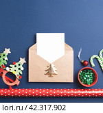 Top view of Christmas envelope, white card and holiday decorations on dark blue background. Стоковое фото, фотограф Юлия Трикашная / Фотобанк Лори