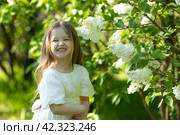 Cute little girl in white dress laughing in spring park near lilac. child smells lilac. Стоковое фото, фотограф Ирина Михайличенко / Фотобанк Лори