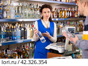 Seller recommends high-quality vodka to man buyer in alcohol department of Russian store. Стоковое фото, фотограф Яков Филимонов / Фотобанк Лори