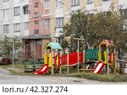 Разноцветная детская площадка в городском дворе возле старого панельного дома. Проблемы благоустройства старых городских кварталов в регионах России. На улице безлюдно. Стоковое фото, фотограф Андрей Степанов / Фотобанк Лори