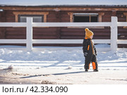 Portrait of a little boy in a yellow hat. The child runs through puddles on the farm, has fun and plays. It's a sunny day. Early spring. The first drop. Стоковое фото, фотограф Photojuli / Фотобанк Лори