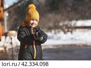 Portrait of a little boy in a yellow hat. The child runs through puddles on the farm, has fun and plays. It's a sunny day. Early spring. The first drop. Стоковое фото, фотограф Photojuli / Фотобанк Лори