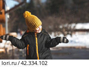 Portrait of a little boy in a yellow hat. The child runs through puddles on the farm, has fun and plays. It's a sunny day. Early spring. The first drop. Стоковое фото, фотограф Photojuli / Фотобанк Лори