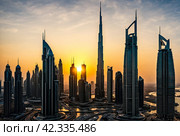 Evening view of silhouettes Dubai city modern skyscrapers at sunset background. Cityscape UAE city with new towers at dusk sky. Construction and modern architecture concept. Copy ad text space, poster. Стоковое AI-изображение, AI-художник Aleksandr Golubev / Фотобанк Лори