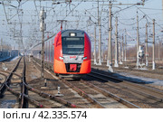 Современный электропоезд ЭС2Г-144 "Ласточка" прибывает на станцию  солнечным мартовским днем. Октябрьская железная дорога (2024 год). Редакционное фото, фотограф Виктор Карасев / Фотобанк Лори