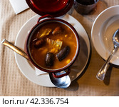 There is traditional Spanish dish on table - Fabada Asturian in pot. Стоковое фото, фотограф Яков Филимонов / Фотобанк Лори