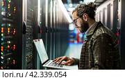 Technician with a laptop checking Server in the data center. Стоковое AI-изображение, AI-художник Ирина Ручушкина / Фотобанк Лори