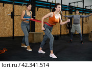 Woman straining against resistance band in gym workout. Стоковое фото, фотограф Яков Филимонов / Фотобанк Лори