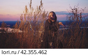 Young girl is dancing in the grass against the background of the sunset. Стоковое видео, видеограф Strunov David / Фотобанк Лори