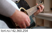 Playing the guitar. Strumming acoustic guitar. Musician plays music. Man fingers holding mediator. Man hand playing guitar neck in dark room. Unrecognizable person rehearsing, fretboard close-up. Стоковое видео, видеограф Марина Демидюк / Фотобанк Лори