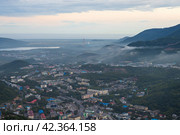 Город Петропавловск-Камчатский, Камчатский край, Дальний Восток России. Вечерний городской пейзаж. Вид сверху на здания, улицы и холмы. Вдалеке ТЭЦ. Стоковое фото, фотограф Андрей Степанов / Фотобанк Лори