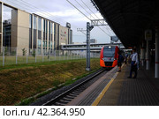 Прибытие поезда Ласточка на станцию метро Балтийская МЦК, Москва. Arrival of a train into Baltiyskaya railway station of the Moscow Central Circle. Summer sunset view. (2021 год). Редакционное фото, фотограф Александр Кузнецов / Фотобанк Лори