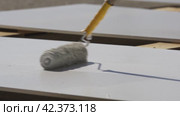 Валиком красят поверхность в белый цвет Use a roller to paint the surface white. Стоковое видео, видеограф Опока Алексей / Фотобанк Лори